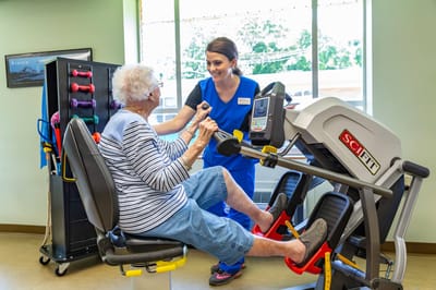 Staff assisting a resident with exercise equipment
