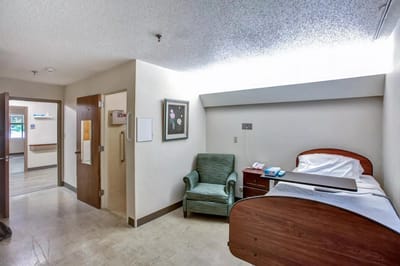 A private resident room with a bed and chair
