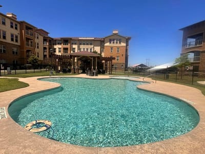 Swimming pool area with patio and buildings in background