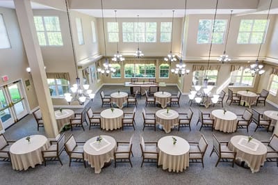 A bright community room with tables and chairs set up