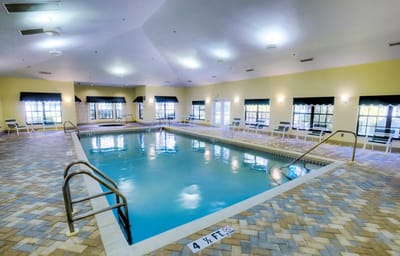 Indoor pool area with lounge chairs and safety signs
