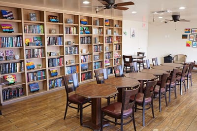 Interior view of a cozy common area with a bookshelf and tables