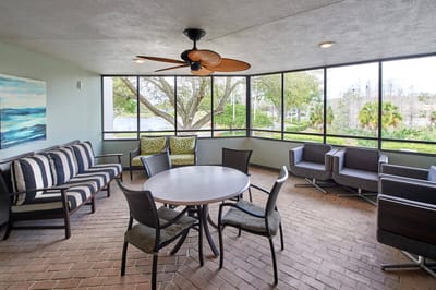 Bright outdoor seating area with a fan and greenery