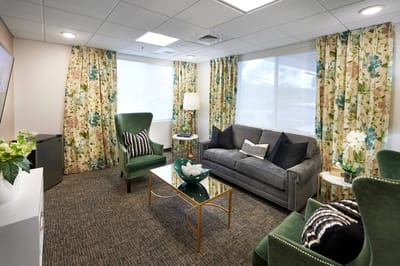 A cozy common area with green chairs and curtains