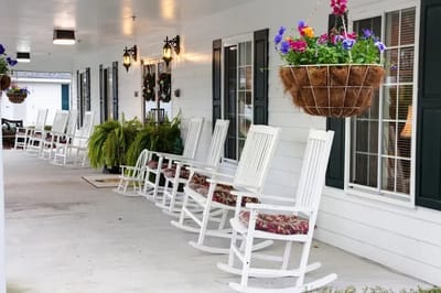 Exterior view of a porch with rocking chairs and hanging flowers