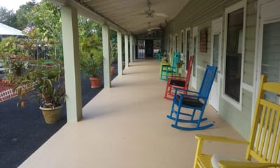 Colorful rocking chairs line a breezy hallway