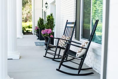 Two rocking chairs on a porch with flowers