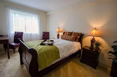 Cozy resident room with bed, desk, and lamps