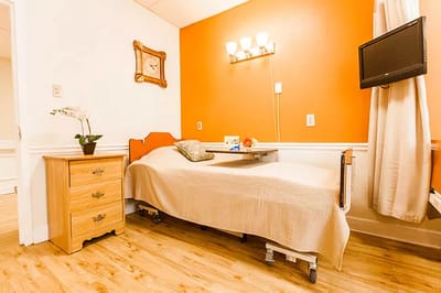 A cozy resident room with orange walls and a bed