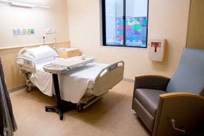 Cozy interior of a patient room with bed and chair
