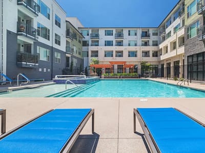 Swimming pool area with lounge chairs and residential buildings