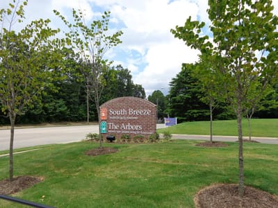 Sign for South Breeze Senior Living amidst landscaped trees