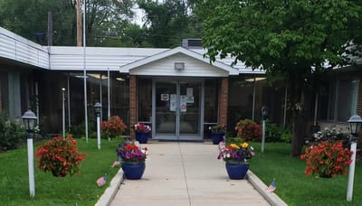Entrance with flowers and flags at the facility