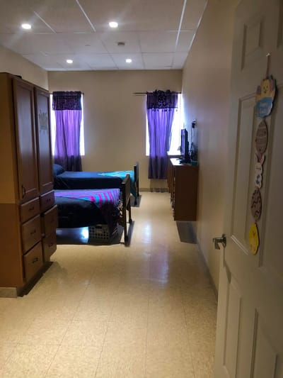 A private resident room with two beds and windows
