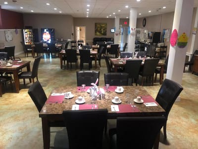 Dining room set up for a meal with tables and chairs