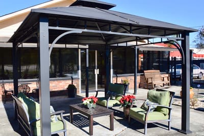 Outdoor shaded seating area with green chairs and flowers