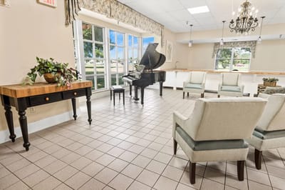 Bright activity room with a grand piano and seating area