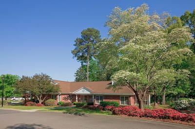 Exterior view of a senior living facility surrounded by trees and flowers