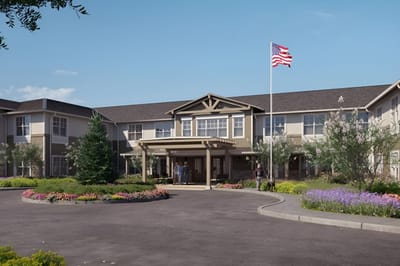 Exterior view of a senior living facility with gardens and flag