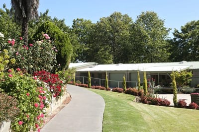 Pathway surrounded by flowers leading to a facility building