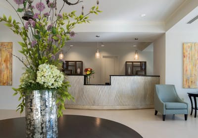 Bright lobby with a reception desk and floral arrangement
