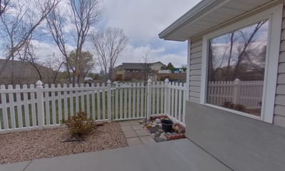 View of an outdoor space with a white fence and landscaped yard