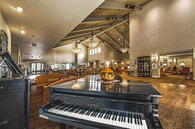 Interior view of a bright common area with seating and piano