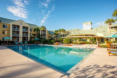 Outdoor pool area with surrounding buildings and palm trees