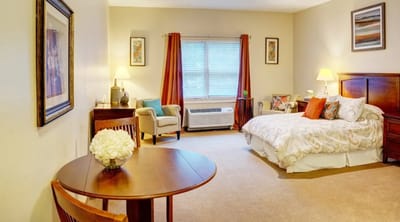 A well-furnished private resident room with a bed and seating area