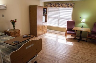 A cozy resident room with a bed and seating area