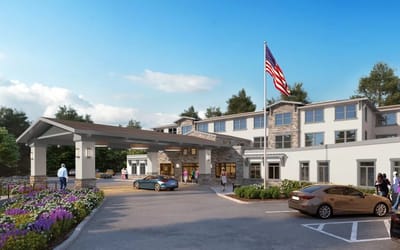 Exterior view of an assisted living facility with flowers and cars