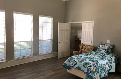 A cozy resident room with a bed and chair