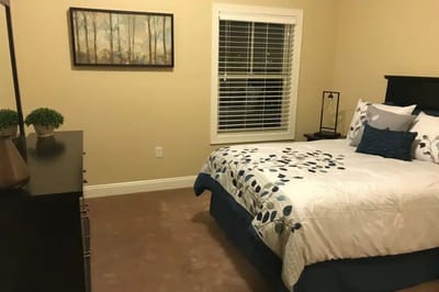 A well-decorated private resident room with a bed and dresser