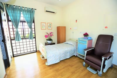 Interior of a private resident room with bed and chair