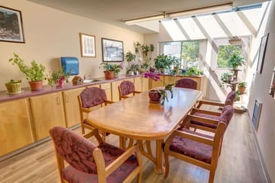 Bright common area with plants and a wooden table