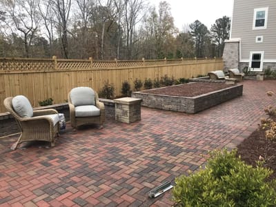 Paved outdoor seating area with chairs and flower beds