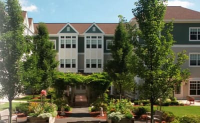 Exterior view of the assisted living facility with gardens and trees
