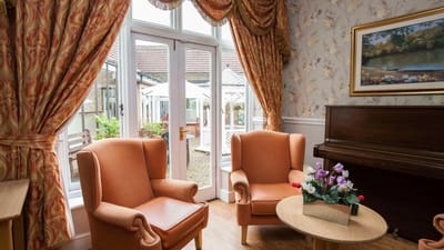 Cozy seating area with orange chairs and piano