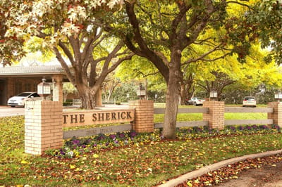 Entrance sign for The Sherick facility surrounded by trees