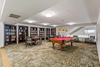 A cozy common area with bookshelves and a pool table