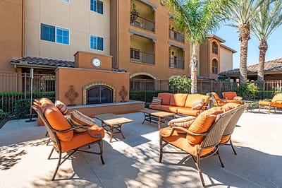Outdoor seating area with orange furniture and palm trees.
