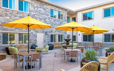 A sunny outdoor courtyard with yellow umbrellas and seating