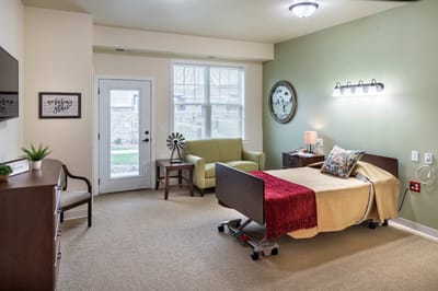 A private resident room with a bed, chair, and window