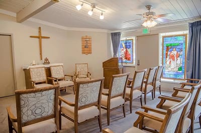 Chapel interior with rows of chairs and stained glass windows