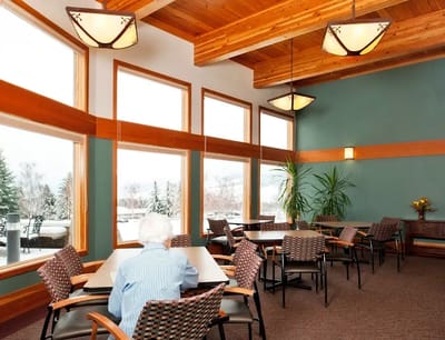 A resident sitting in a sunlit common area with large windows