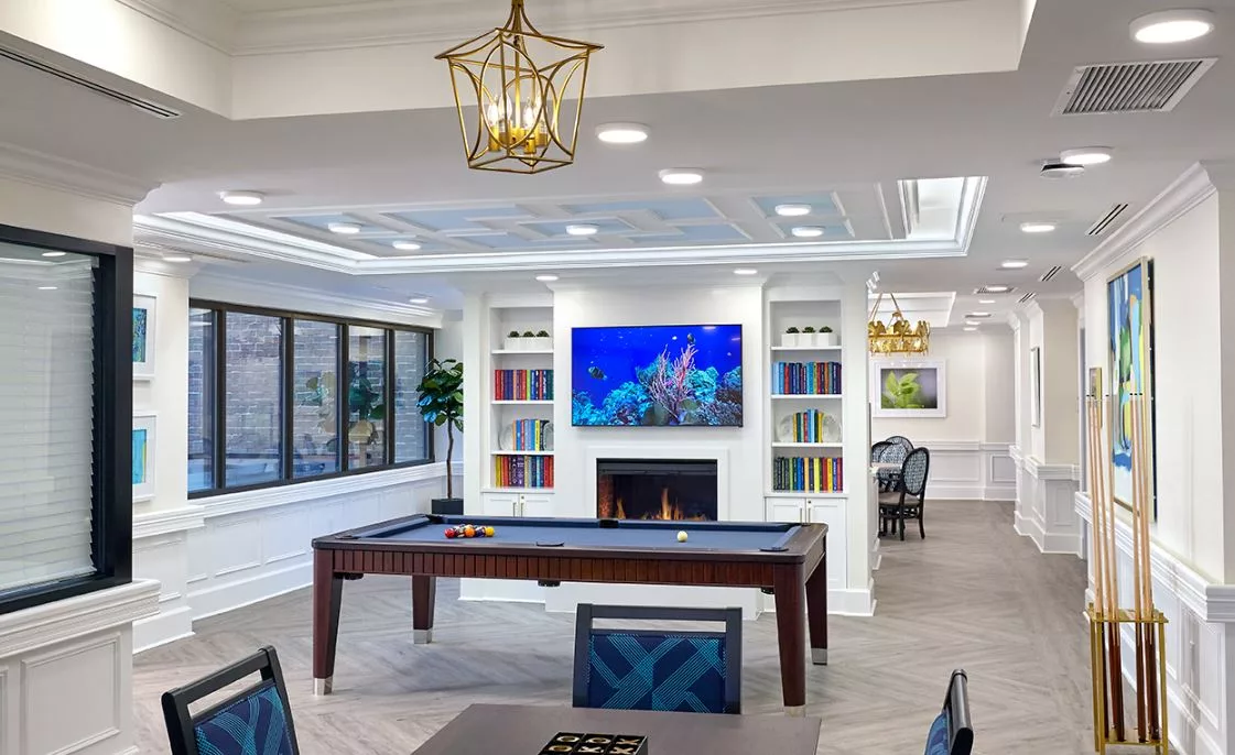 Bright interior common area with a pool table and fireplace