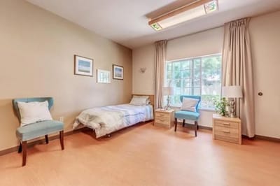 A private resident room with a bed and two chairs