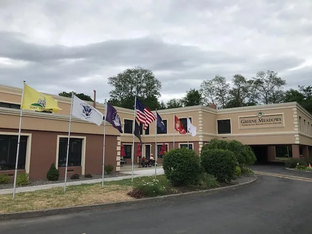 Exterior view of Greene Meadows Nursing with flags
