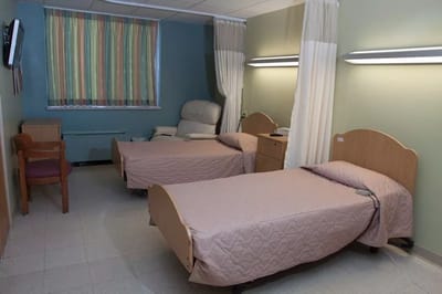 A cozy resident room with two beds and a recliner