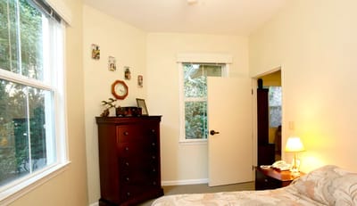 A cozy private resident room with a window and dresser